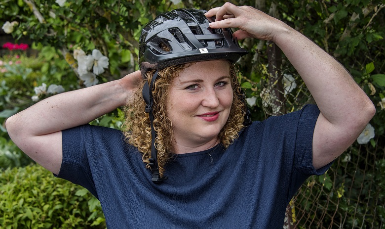 Stefanie F. Eine junge Frau mit bloden Locken zieht einen Helm an.